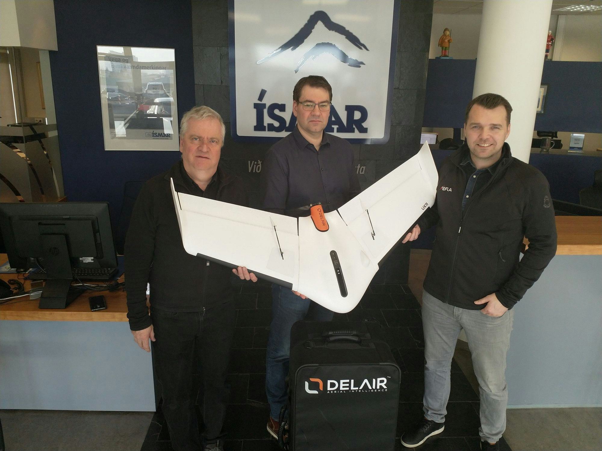 Three men posing with a white airplane model 